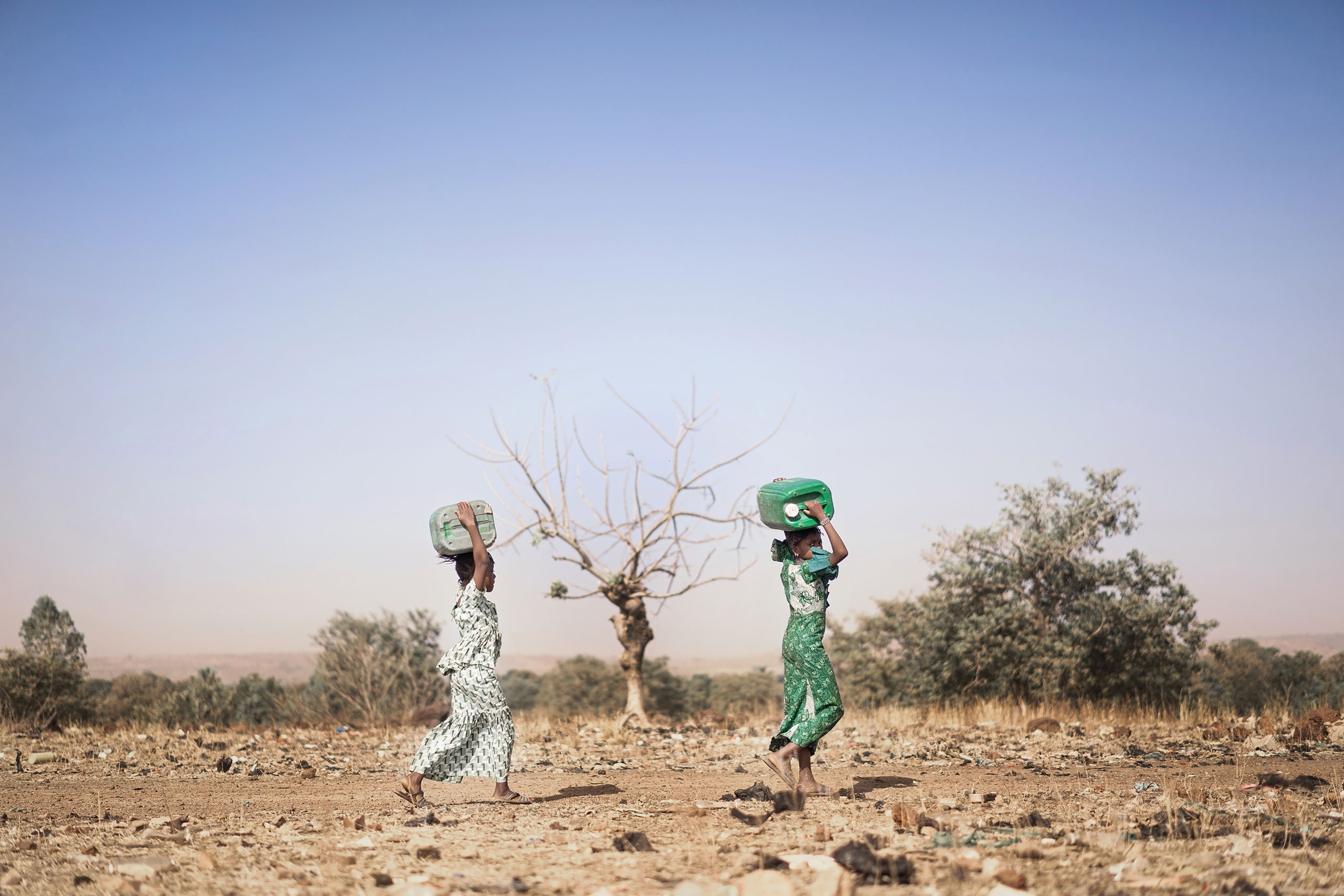 Two women carrying jugs of water on their heads